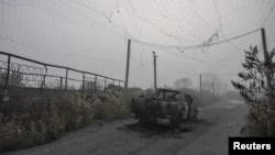 Izgoreli pikap ispod pocepane mreže za odbranu od dronova na sredini puta blizu Huljajpolja.