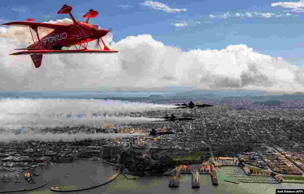 A Team Oracle aerobatics pilot flies above the U.S. Navy Blue Angels over San Francisco. (AFP/Josh Edelson)