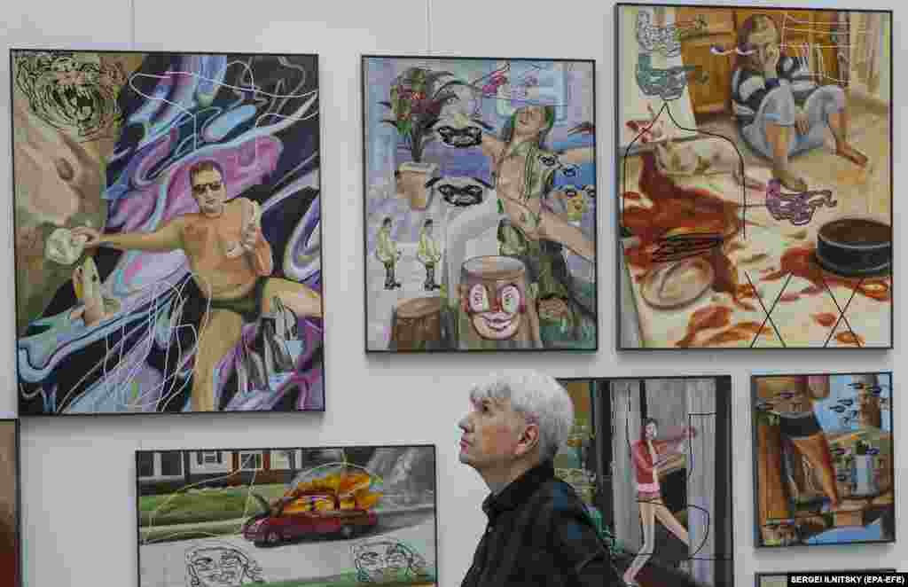 A visitor examines artworks by Ivan Gorshkov of Russia.