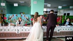 O mireasă și un mire votează la o secție de votare din Horesti, Moldova, pe 28 septembrie 2025.