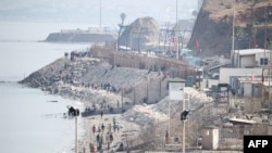 Migranții merg de-a lungul țărmului, în apropierea gardului de frontieră care separă Marocul de exclava spaniolă Ceuta din Africa de Nord, întorcându-se în Maroc, pe 1 august 2026.
