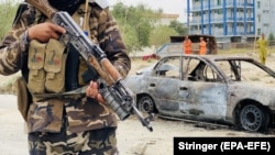 A Taliban fighter stands guard near a vehicle that was used to fire rockets at the airport in Kabul on August 30.