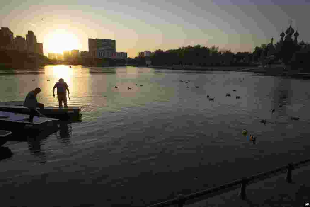 Boatmen work on Moscow&#39;s Great Palace Pond with the Church of the Holy Trinity in Ostankino in the background.&nbsp;