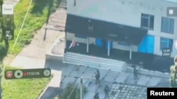 Armed personnel pull down a Russian national flag hoisted on a building in Vnezapnoe, Kursk region, Russia, in this screen grab from a video released on August 14.