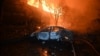 A burnt car is pictured in front of a burning house following a Russian drone strike in Kharkiv, Ukraine, on June 11.