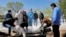 People wearing protective clothing, masks and gloves, attend the funeral of a victim who died of new coronavirus, at a cemetery just outside Tehran, March 30, 2020