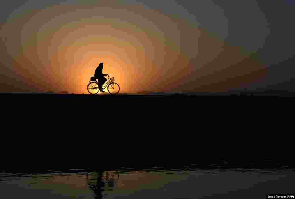 An Afghan man rides a bicycle along a road at sunset in the Arghandab district of Kandahar Province. (AFP/Javed Tanveer)