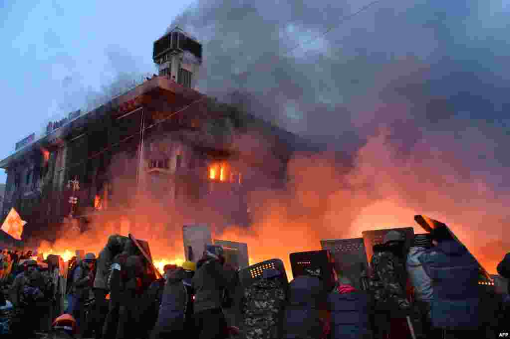 Protestatarii antiguvernamentali de la Kiev se protejează cu scuturi în timpul ciocnirilor de astăzi, la primele ore ale zilei, cu poliția. 