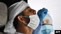 Для диагностического теста на COVID-19 медицинский работник берет образец слизи из носа жителя Дубая.