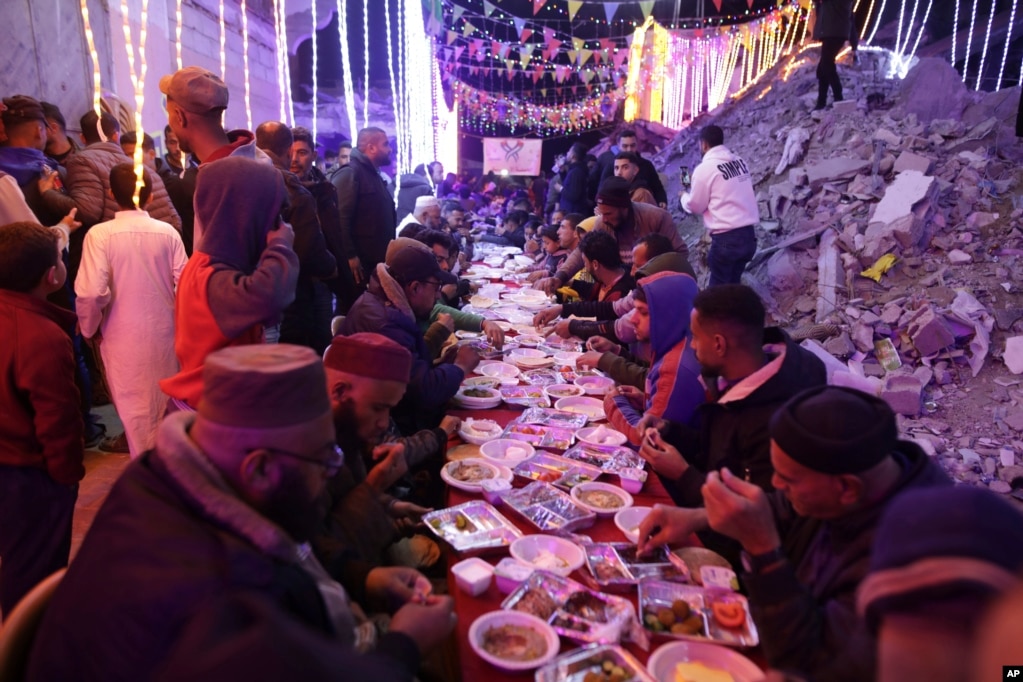 Palestinezët duke ngrënë syfyr të përbashkët pranë shtëpive të tyre të shkatërruara në Han Junis.