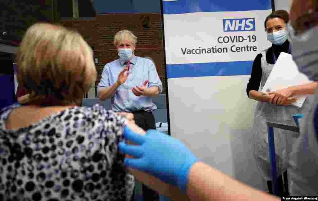 Премьер-министр Великобритании Борис Джонсон аплодирует после того, как медсестра Ребекка Катерсайдс ввела вакцину Pfizer/BioNTech COVID-19 Лин Уиллер в больнице Гая в Лондоне. Великобритания, 8 декабря 2020 года