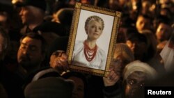 An opposition supporter at a protest rally in Kyiv on November 12 holds up a portrait of jailed opposition leader Yulia Tymoshenko.