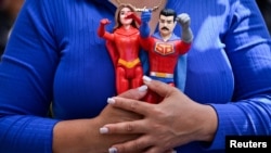 عروسک‌های مادورو و همسرش در دست یکی از هواداران او در کاراکاس ونزوئلا، ۱۳ دی‌ماه
