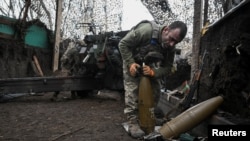 Артилерист 152-ї ОЄБр ЗСУ готує снаряди для гаубиці, поки його побратими ведуть вогонь у бік російських військ поблизу прифронтового міста Покровськ, Донецька область, грудень 2025 року