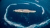 Revolutionary Guard speed boats circle around a replica aircraft carrier during a military exercise, in the strategic Strait of Hormuz, July 28, 2020 