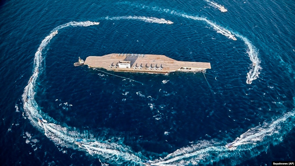 Revolutionary Guard speed boats circle around a replica aircraft carrier during a military exercise, in the strategic Strait of Hormuz, July 28, 2020 