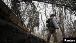 Артилерист 152-ї ОЄБр ЗСУ несе патрон до гаубиці після закінчення вогневої роботи в бік російських військ поблизу міста Покровськ, Донецька область, 11 грудня 2025 року