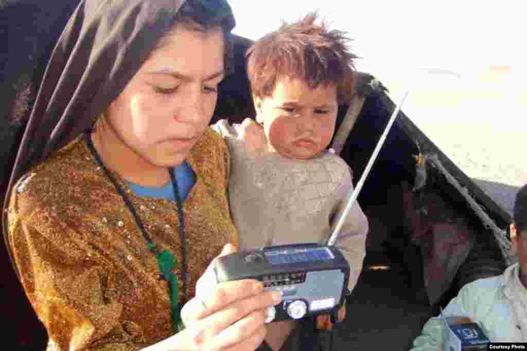 A woman in a a camp of Kuchi nomads in Shindand province examines her new radio. The radios are equipped with solar panels and a hand-crank for easy, battery-free charging, and also feature a torch and cell phone charger.