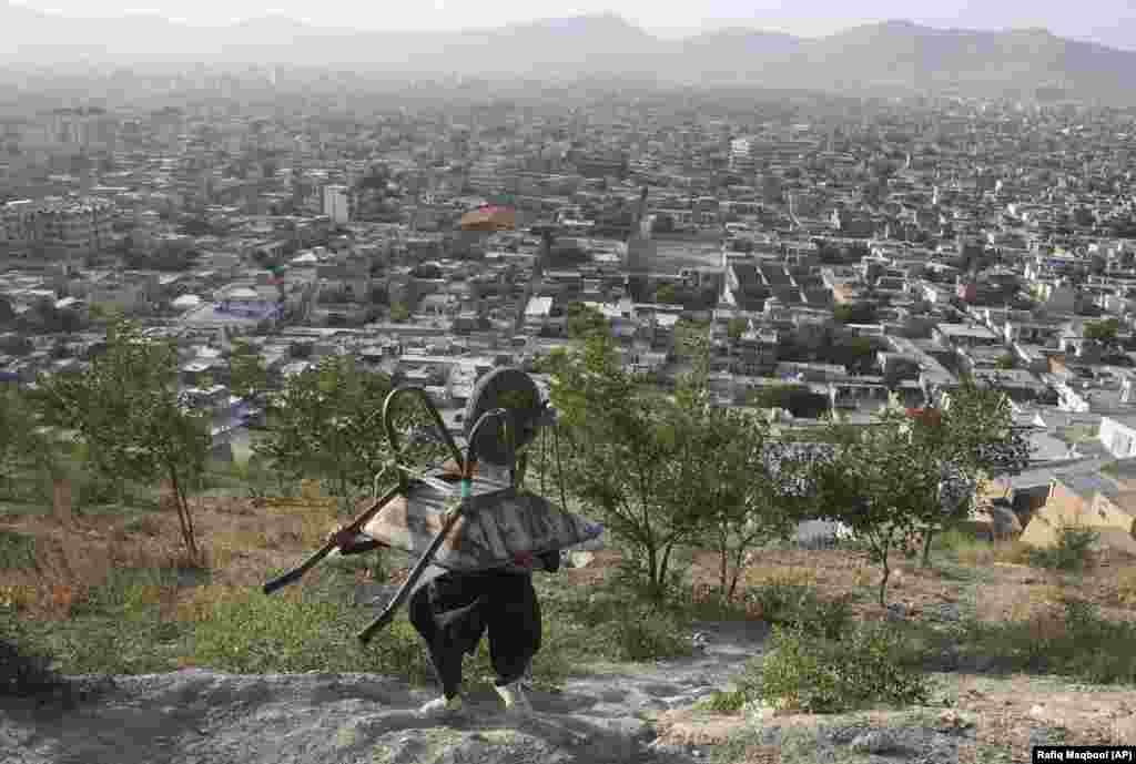 An Afghan boy carries his wheelbarrow in the mountains above Kabul. (AP/Rafiq Maqbool)