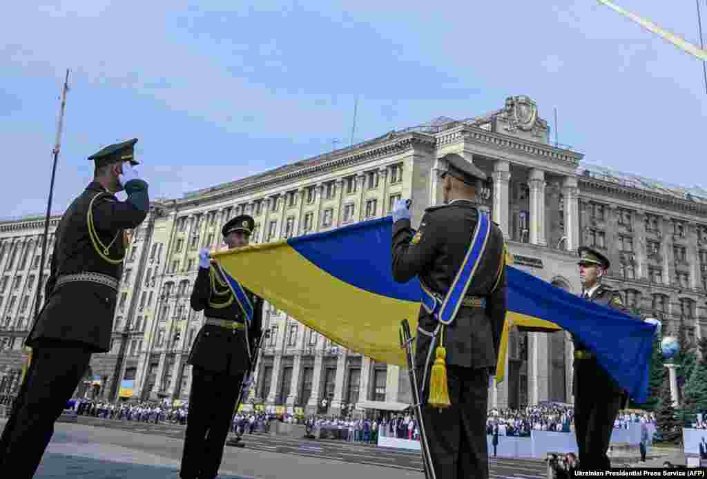 Ukrainian soldiers pay their respects to their national flag in Kyiv on August 24.