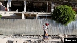 Žena sa djetetom prolazi pored ruševina zgrade oštećene u borbama u gradu Šireu, region Tigraj, Etiopija (17. mart 2021.)