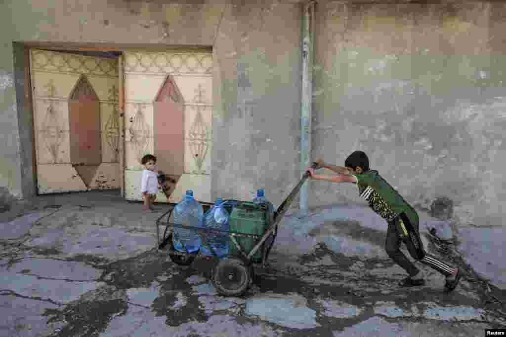 An Iraqi boy pushes water containers along a street in eastern Mosul. (Reuters/Marko Djurica)