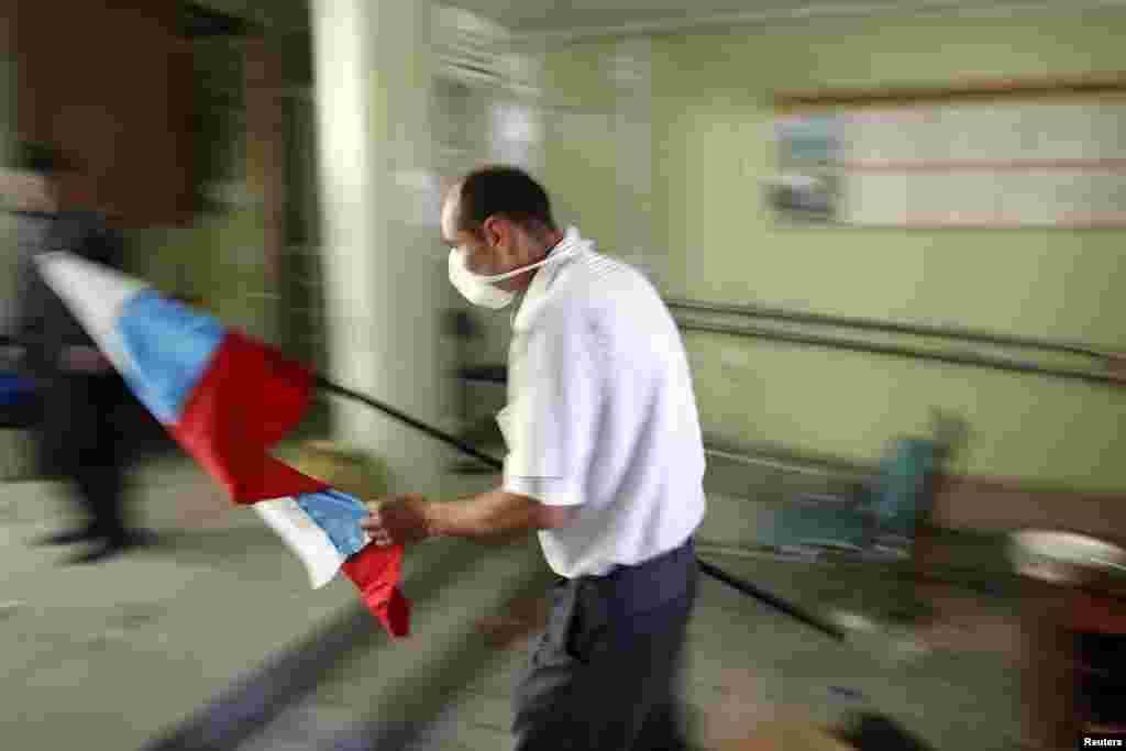 A pro-Russia rebel carries a Russian flag into the city hall in Mariupol, eastern Ukraine. (Reuters/Marko Djurica)