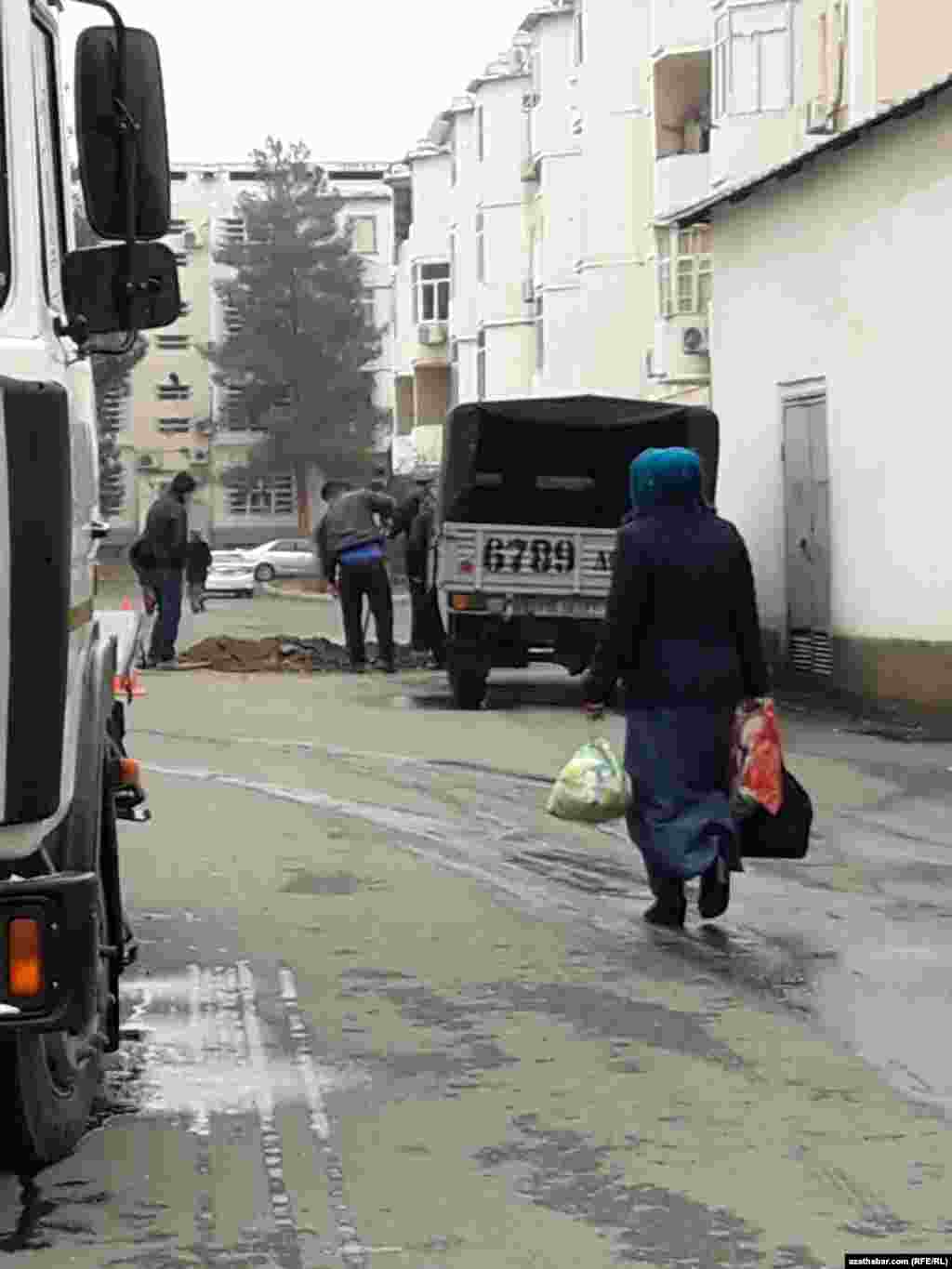 Aşgabatda söwda edip gelýän zenan köp gatly jaýlaryň arasyndaky köçeden ýöräp barýar.
