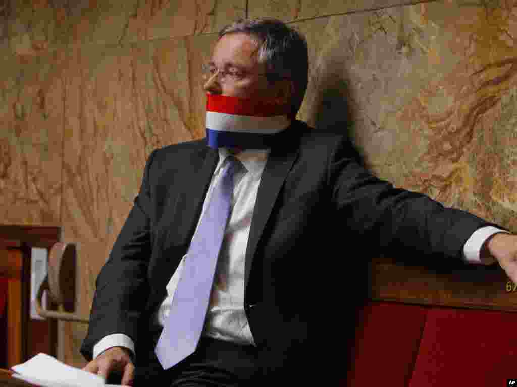 French Deputy Alain Dupont-Aignan protests by using a French flag as a gag during a speech of Prime Minister Francois Fillon on the French intervention in Libya at the National Assembly in Paris.Photo by Jacques Brinon for The AP