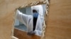 A worker wearing a face mask and a protective suit prepares coffins that are later distributed to hospitals to transport people who have died of the coronavirus.