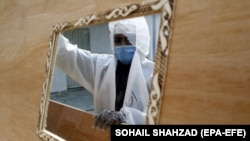 A worker wearing a face mask and a protective suit prepares coffins that are later distributed to hospitals to transport people who have died of the coronavirus.