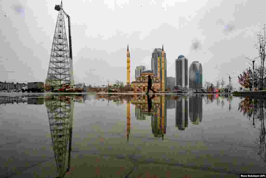 A man walks through a square after snowfall as workers assemble a Christmas tree, with the main mosque and skyscrapers in the background in the Chechnya capital of Grozny. (AP/Musa Sadulayev)