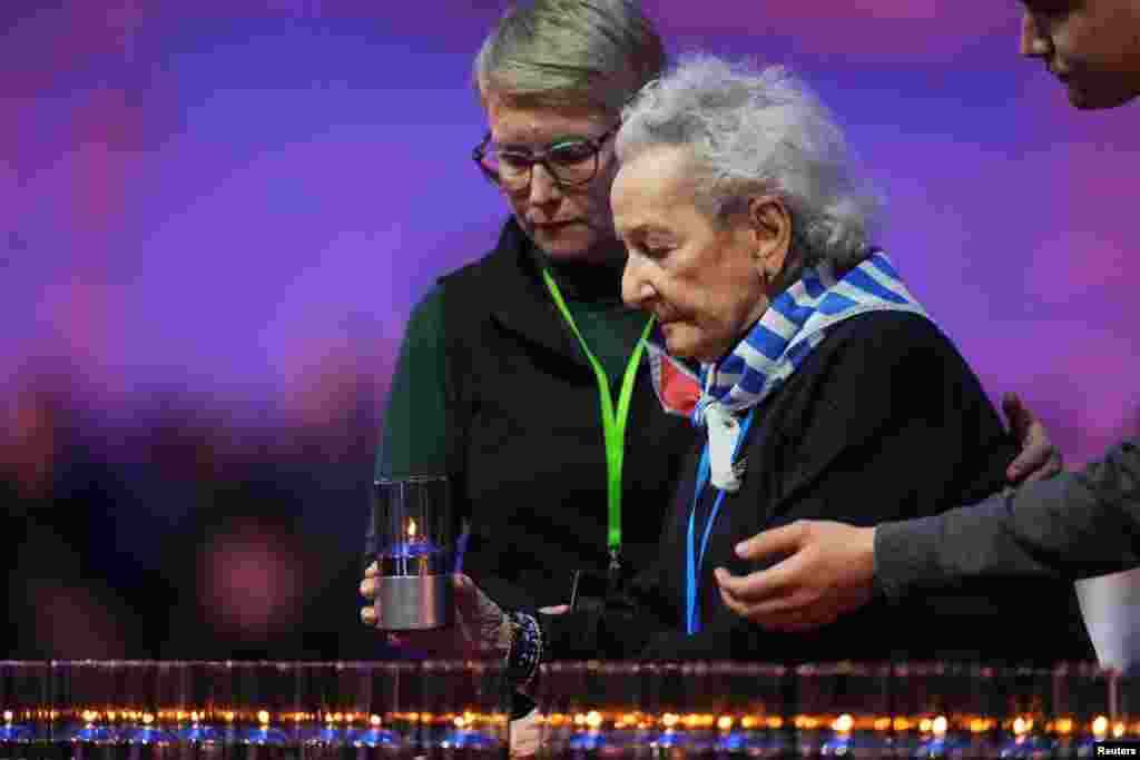 O supraviețuitoare a Holocaustului este ajutată să depună o lumânare.