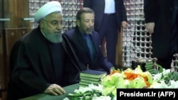 Iranian President Hassan Rohani (left) prays over the tomb of the founder of Iran's Islamic republic, Ayatollah Ruhollah Khomeini, in southern Tehran on January 31.