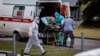 Medics escort an elderly woman into a hospital where patients infected with COVID-19 are being treated, in the settlement of Kommunarka outside Moscow on June 30.