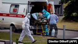 Medics escort an elderly woman into a hospital where patients infected with COVID-19 are being treated, in the settlement of Kommunarka outside Moscow on June 30.