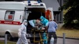 RUSSIA -- Medics escort a woman into a hospital where patients infected with the COVID-19 novel coronavirus are being treated in the settlement of Kommunarka outside Moscow, June 30, 2021