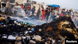کودکان فلسطینی در کنار وسایل سوخته از حمله اسرائیل به اردوگاهی در محله «تل‌السلطان» شهر رفح