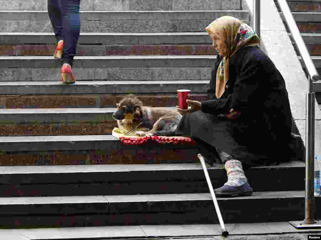 Киев: Пожилая женщина просит милостыню у прохожих в переходе. - An elderly woman with her dog begs for money in Kiev May 18, 2011. REUTERS/Gleb Garanich (UKRAINE - Tags: SOCIETY ANIMALS) 11POTW20