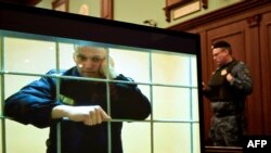 Liderul opoziției Alexei Navalnîi apare pe un ecran instalat la o sală de judecată a Tribunalului orașului Moscova.