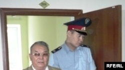 Полицейский выводит бывшего советника акима Западно-Казахстанской области Алпамыса Бектурганова в наручниках из зала суда. Уральск, 13 августа 2009 года. 