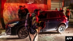 A firefighter holds a helmet as he operates outside a building hit by a projectile on the outskirts of Tel-Aviv on March 6.