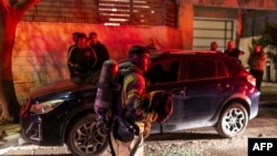 A firefighter holds a helmet as he operates outside a building hit by a projectile in a city in outskirts of Tel-Aviv on March 6, 2026.