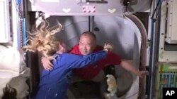АҚШ астронавты Кейт Рубинс халықаралық ғарыш станциясына Жерден ұшып барған жапон астронавты Соити Ногутиді (оң жақта) қарсы алып жатыр. 17 қараша 2020 жыл. NASA видеосынан скриншот.