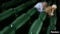 Bosnians mourn over the coffins of victims of the Srebrenica massacre.