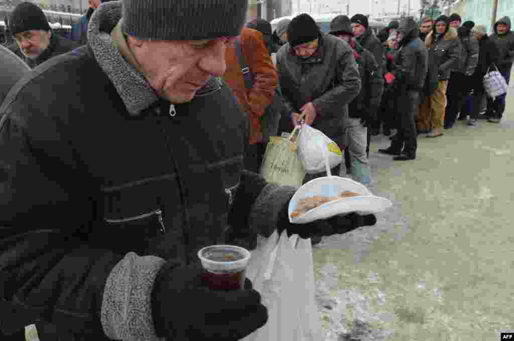 Homeless people line up for free hot food at a kiosk organized by social services in Kyiv.