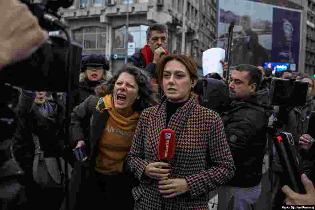 Një gazetare duke raportuar ndërsa aktivistët e rrethojnë gjatë një proteste kundër planit t autoriteteve për të filluar prishjen dhe heqjen e Urës së Vjetër Sava në Beograd.