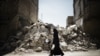 Syria -- A Syrian woman walks past a destroyed building while reaching a food distribution centre in Aleppo on 13Sep2012