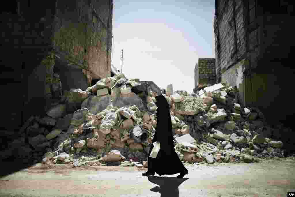 A Syrian woman walks past a destroyed building while reaching a food distribution center in Aleppo. (AFP/Marco Longari)