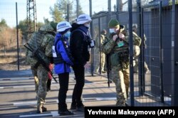 EBESZ-megfigyelők lépnek át egy ellenőrzőponton a Kijev által ellenőrzött területről a lázadók által uralt területre, Scsasztja városban, a Luhankszki körzetben 2020. november 10-én